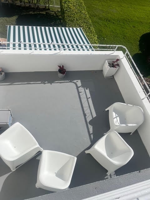 Overhead view of a boat deck with white storage containers and green striped canopy, overlooking lawn